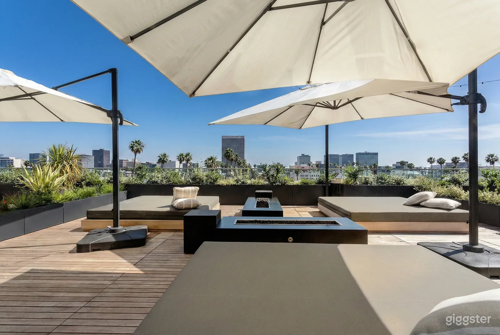 Lounge beds surround an outdoor firepit on an umbrella topped rooftop patio.