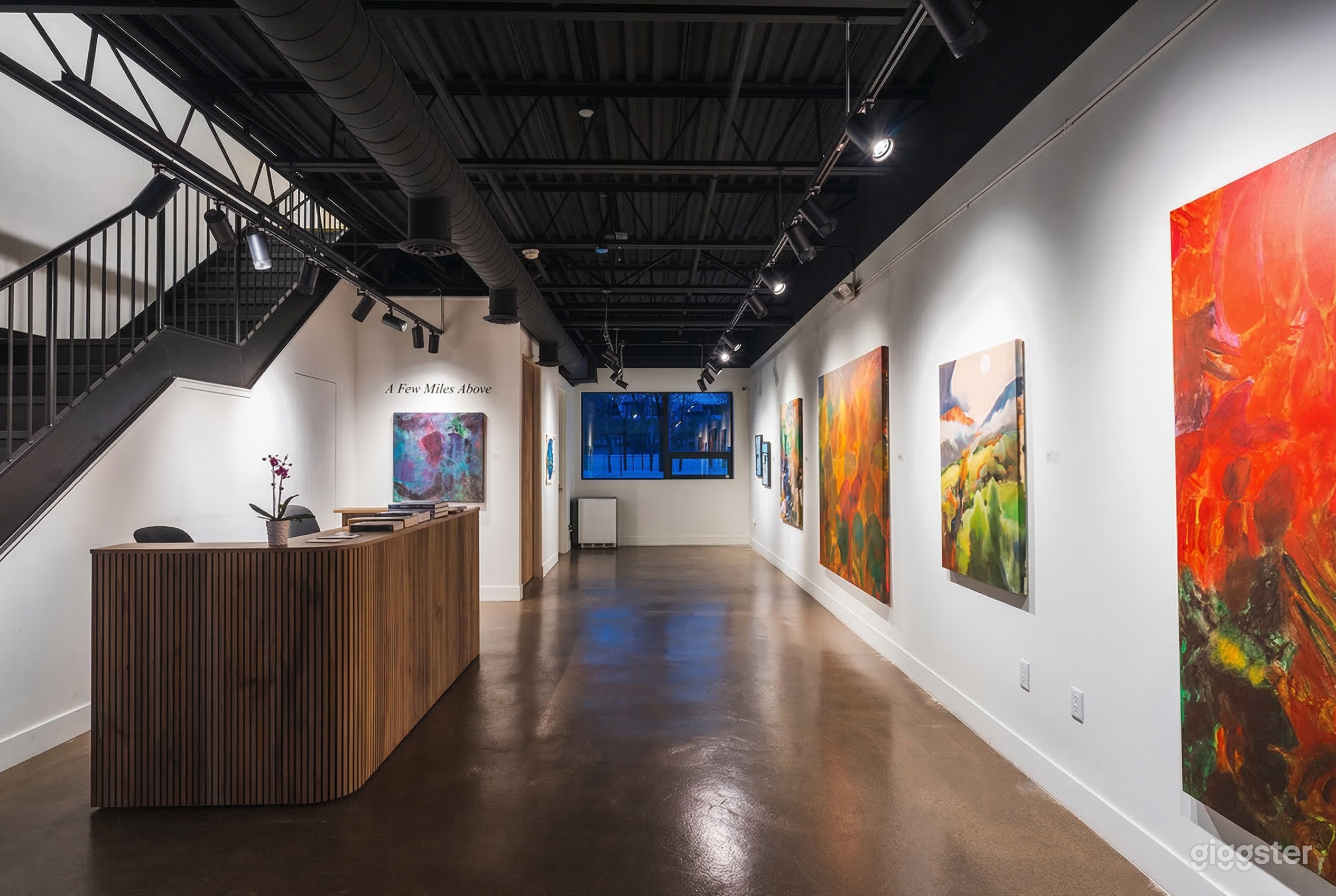 A spacious event hall has paintings on the wall and polished concrete floors.