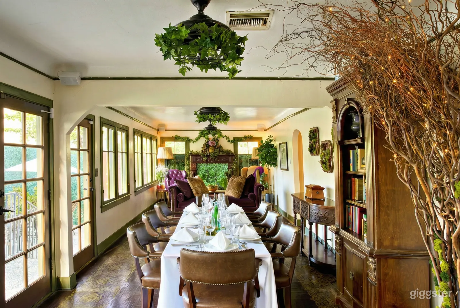 A table decorated in white with glassware in a long dining room, ready for Christmas dinner.