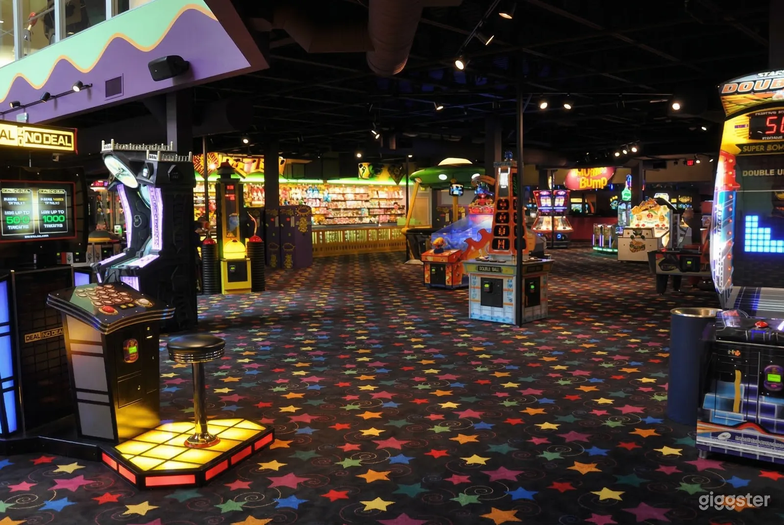 An arcade with a colorful carpet and multiple games machines.