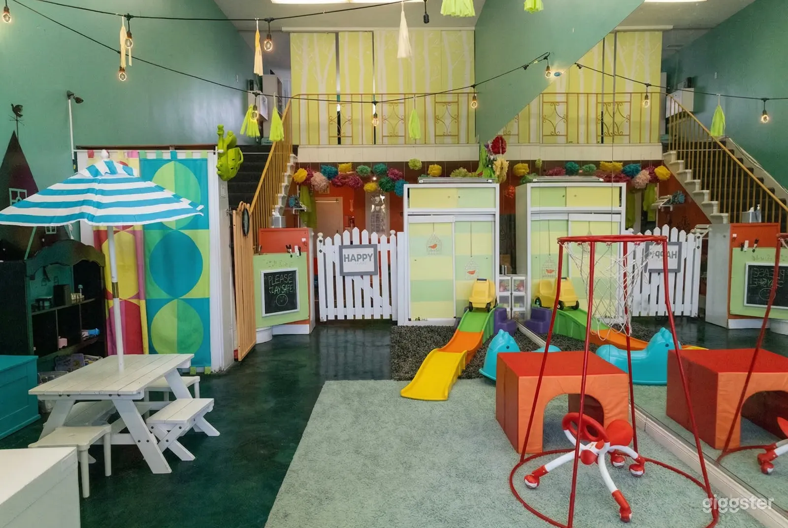 Colorful small children's games room with slides, ride-on toys and basketball hoops.