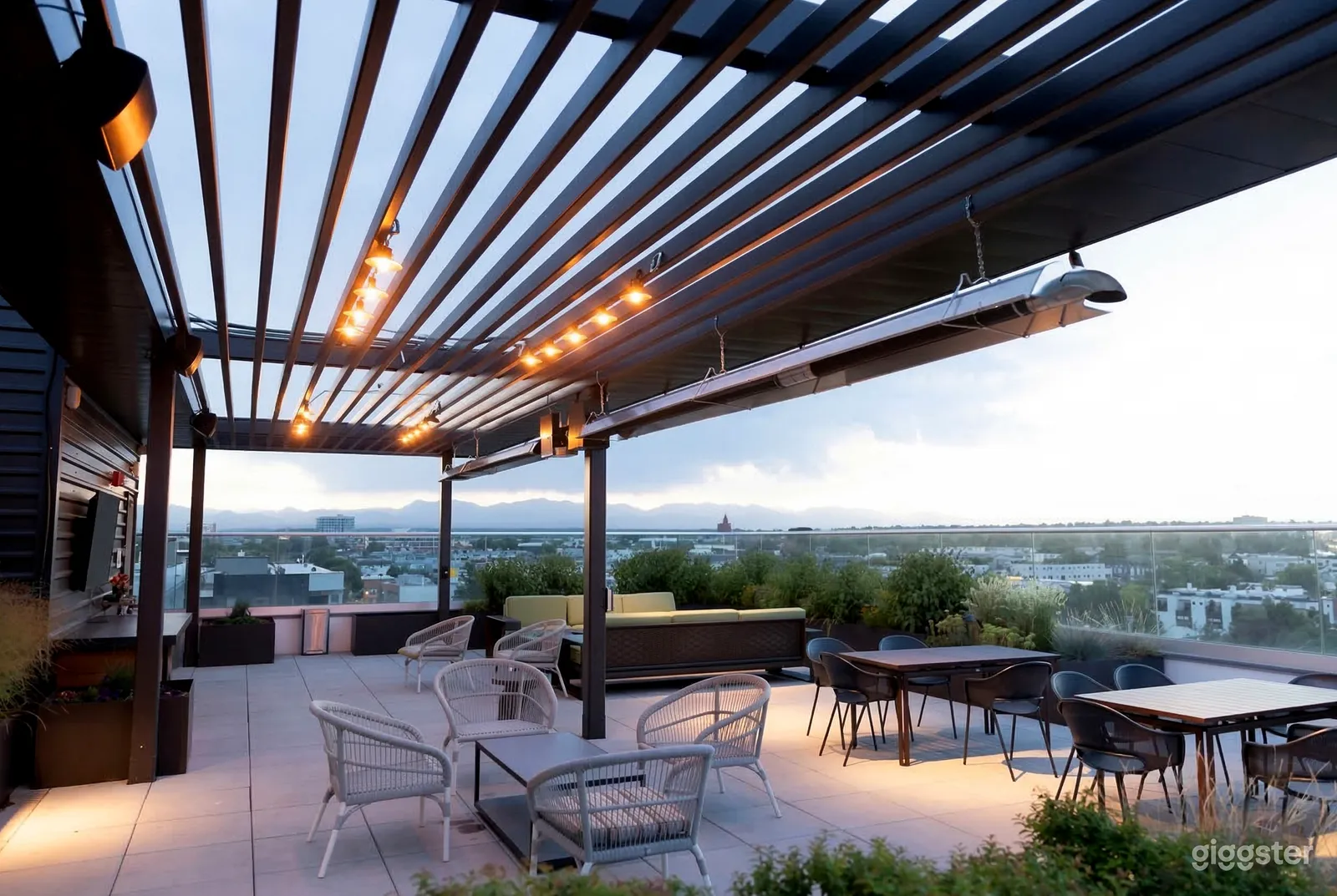 A large rooftop space with a black pergola and varying types of tables and chairs for seating.