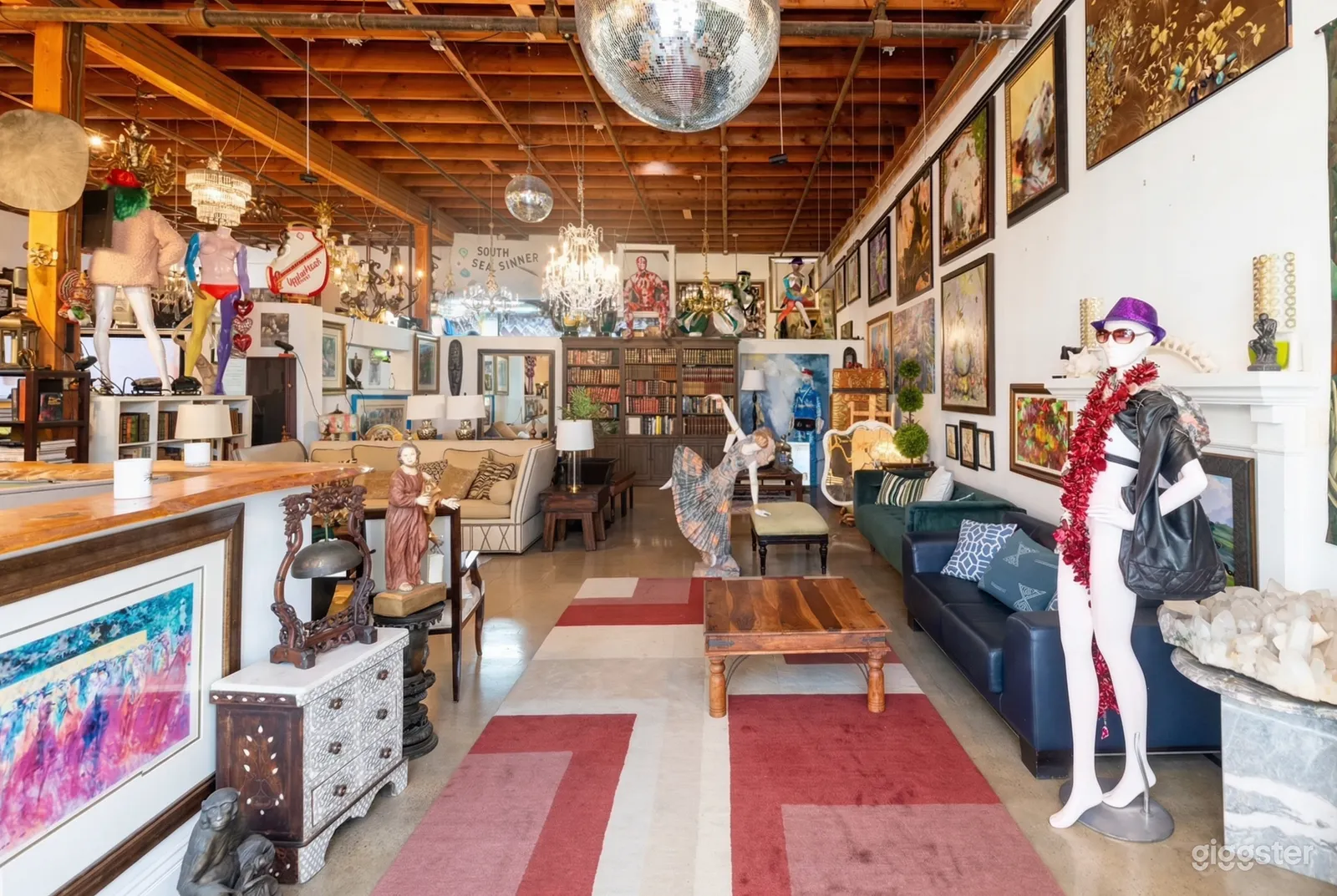 Vintage mannequins, statues, books, and paintings in a room with couch seating.