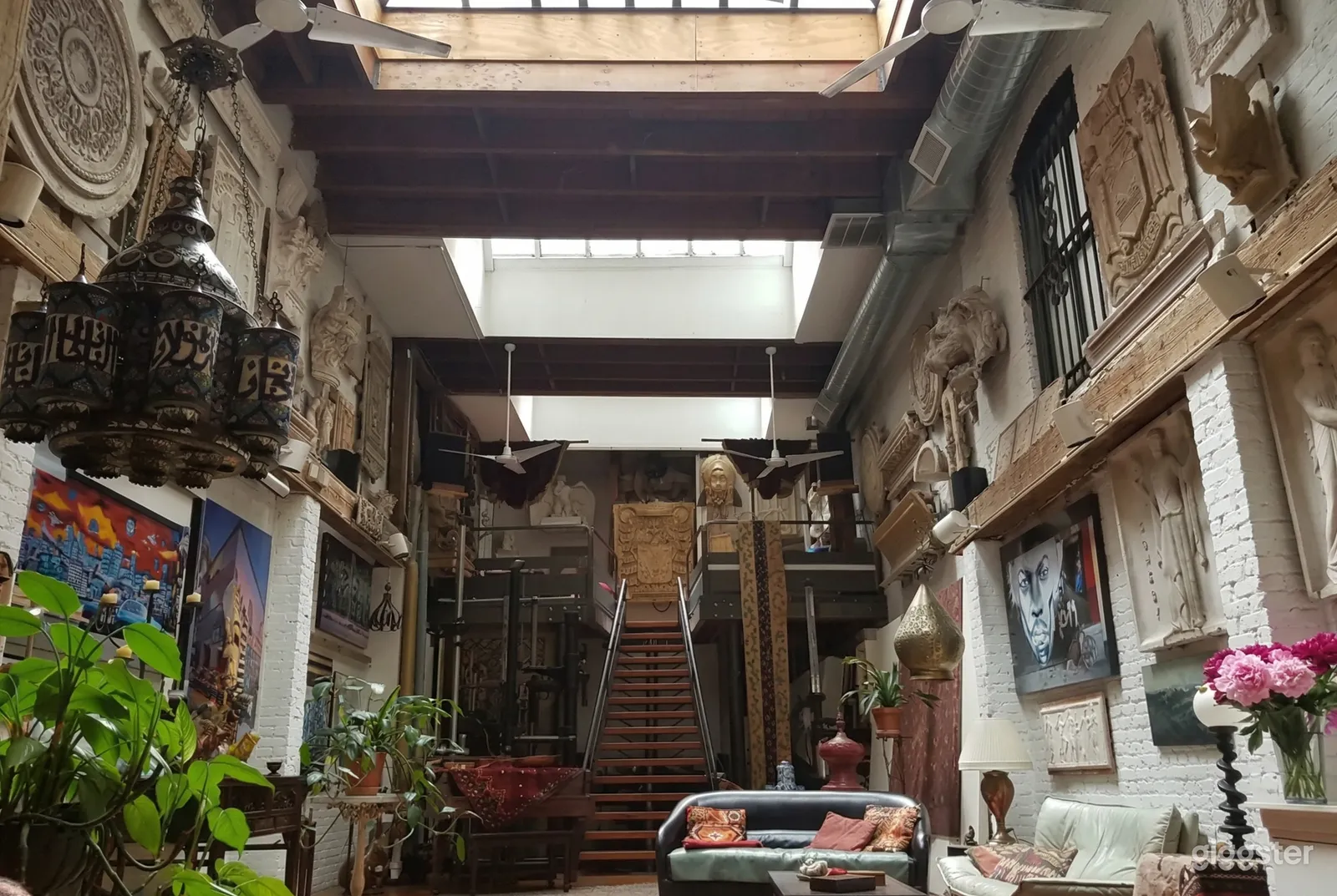 A large room with ornate carvings and decor on the walls, with an industrial style ceiling overhead.