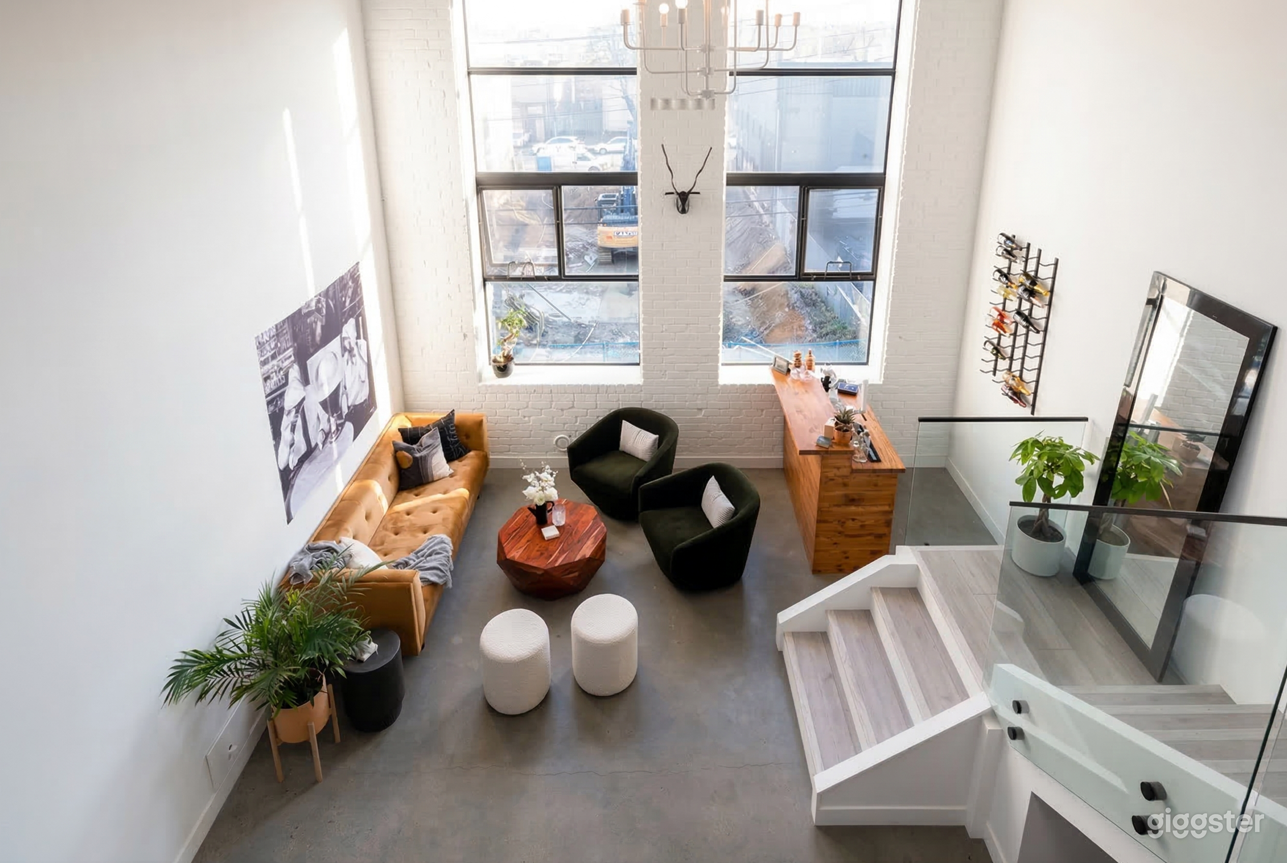 A high ceiling room with white brick walls holds a couch and chairs as well as a reception desk.