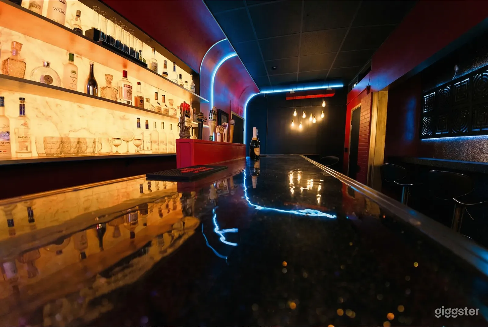 A well-lit bar with multiple bottles overlooks a long shiny bar counter.