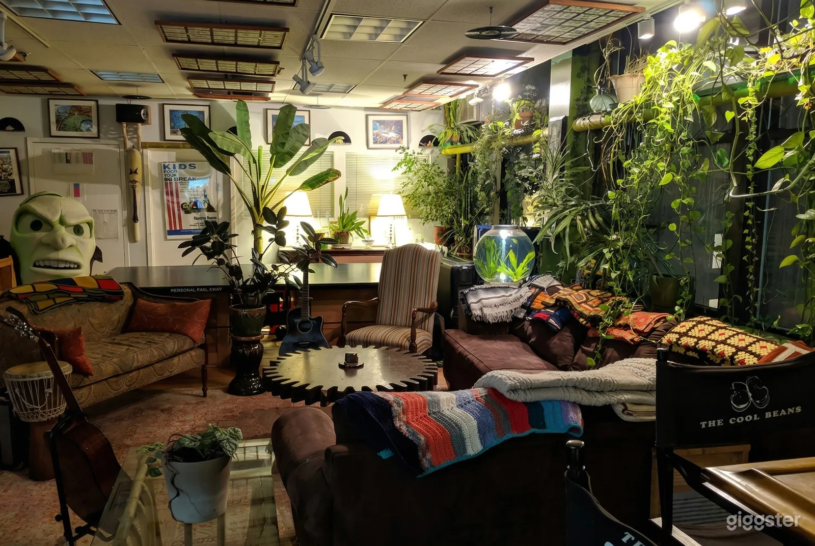A bohemian style classroom has casual seating and a wall of green plants on one side.