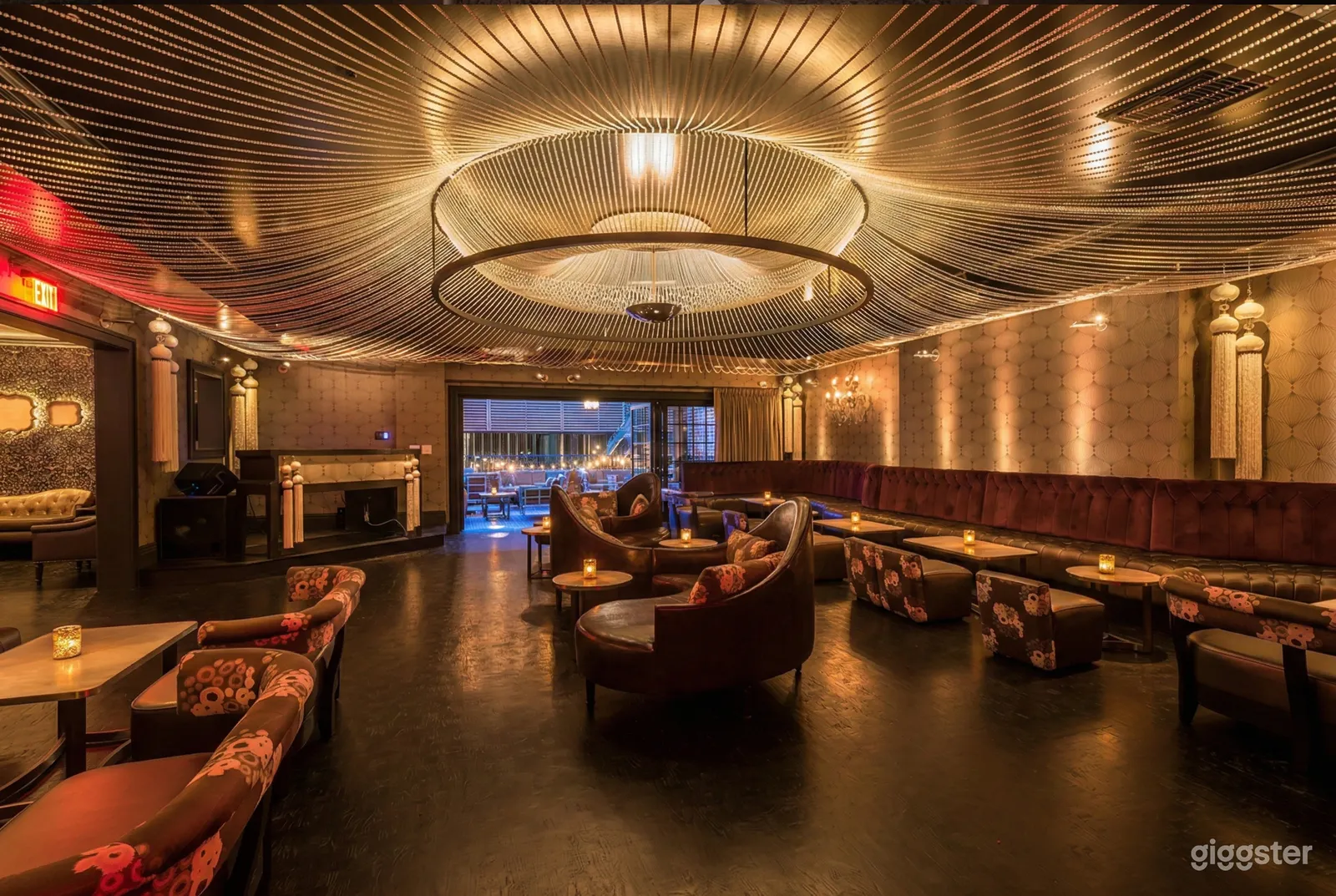A Large restaurant with leather booths, flowered chairs, and extravagant ceiling lighting as the room focus.