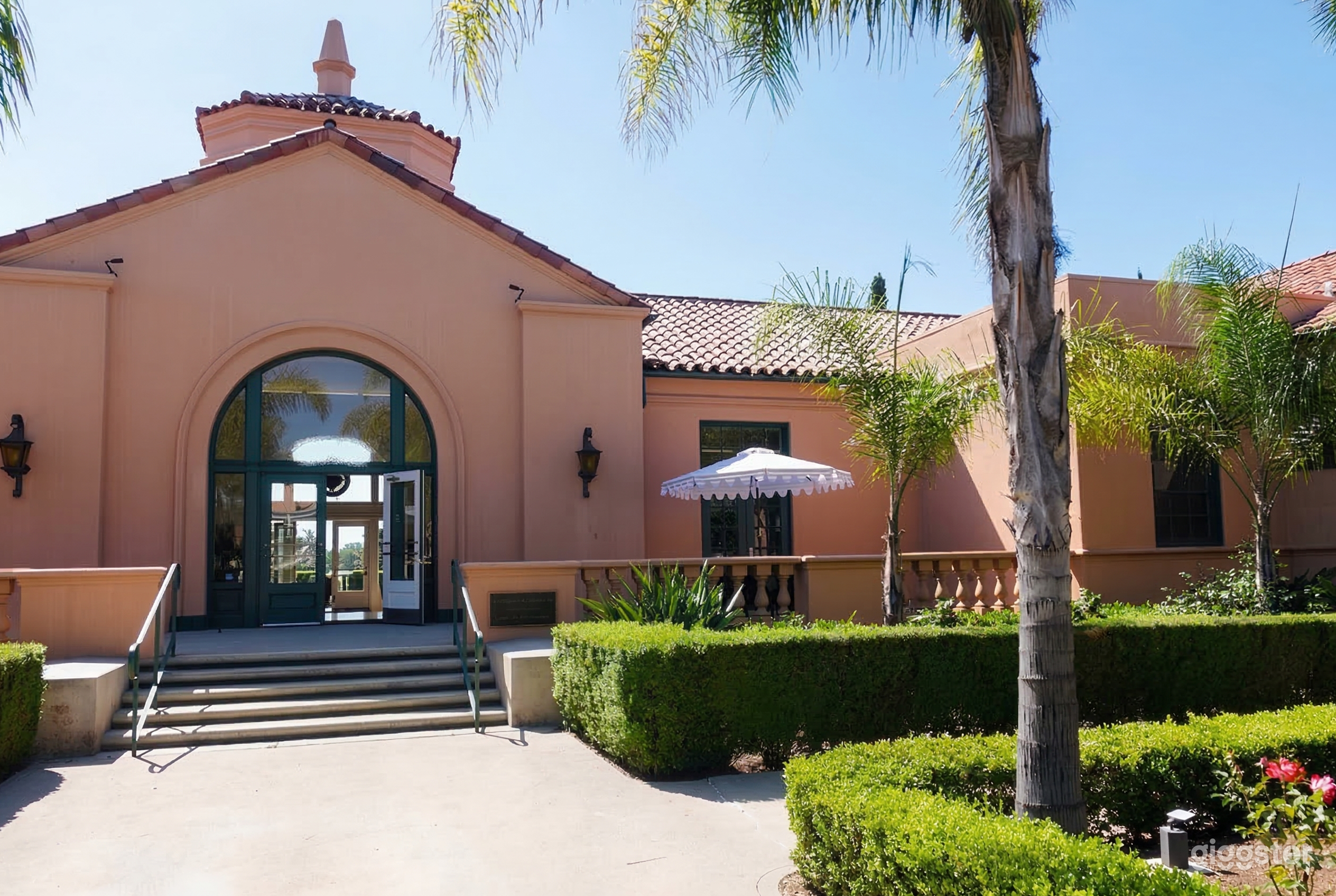 A peach-colored Spanish-style church surrounded by low hedges and with a big entryway.