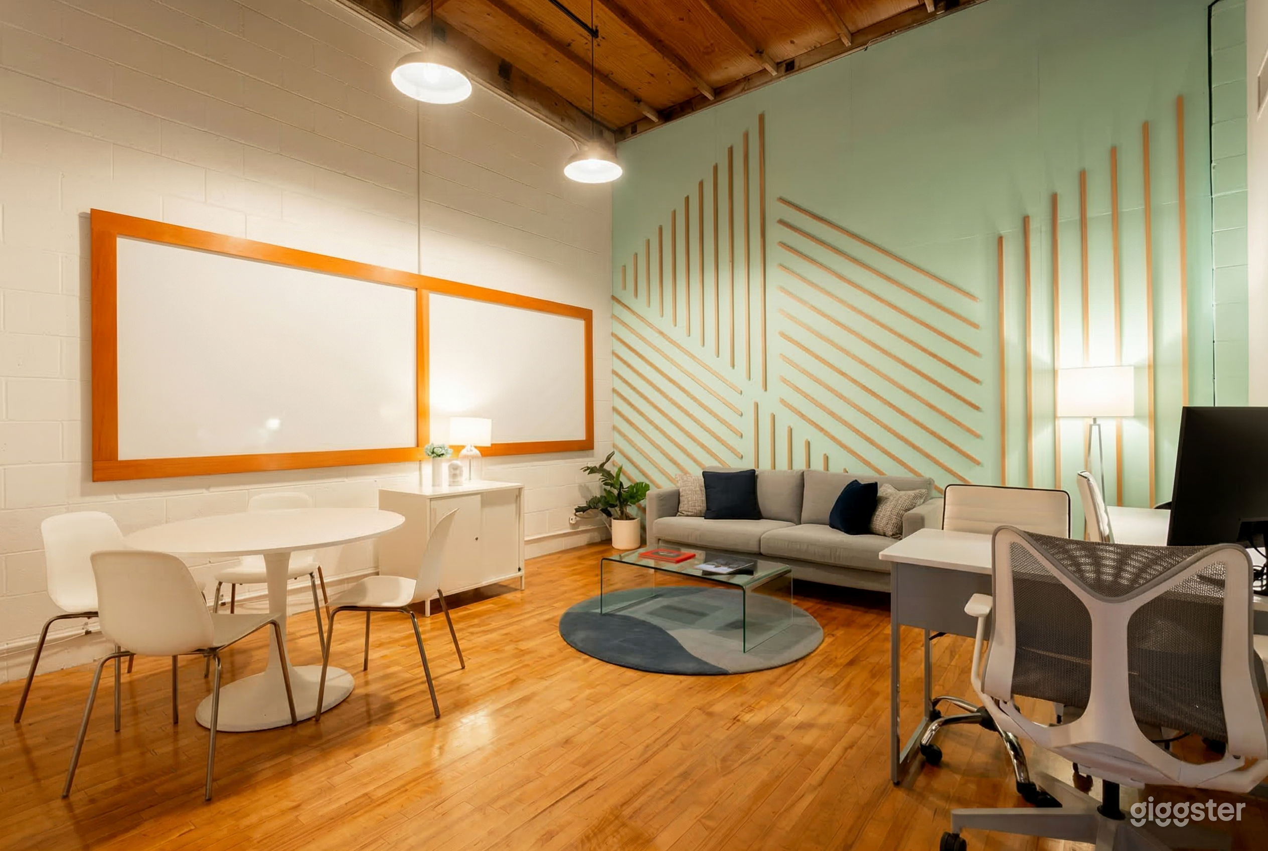 An office with modern wall styling contains a couch, table and chairs, and a desk. 