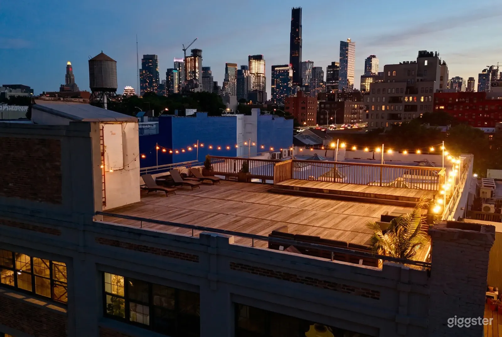 An expansive rooftop terrace has limited seating and string lights around a large part of it.