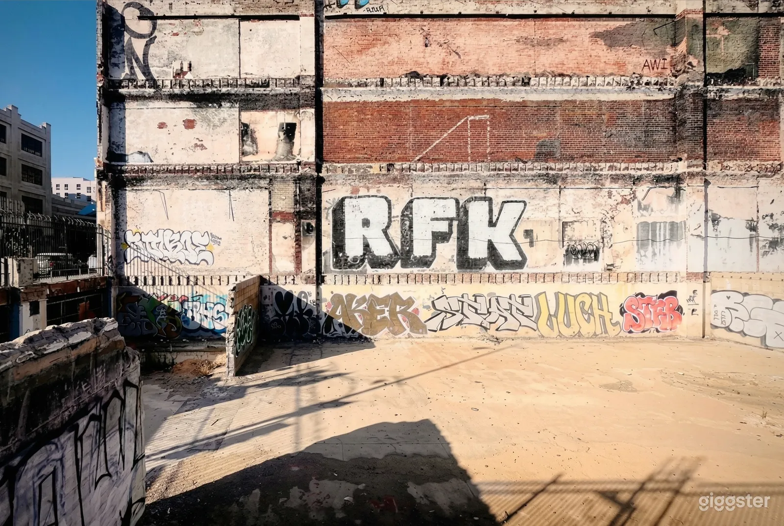 An outdoor enclosed space belonging to a brick building is painted with graffiti.