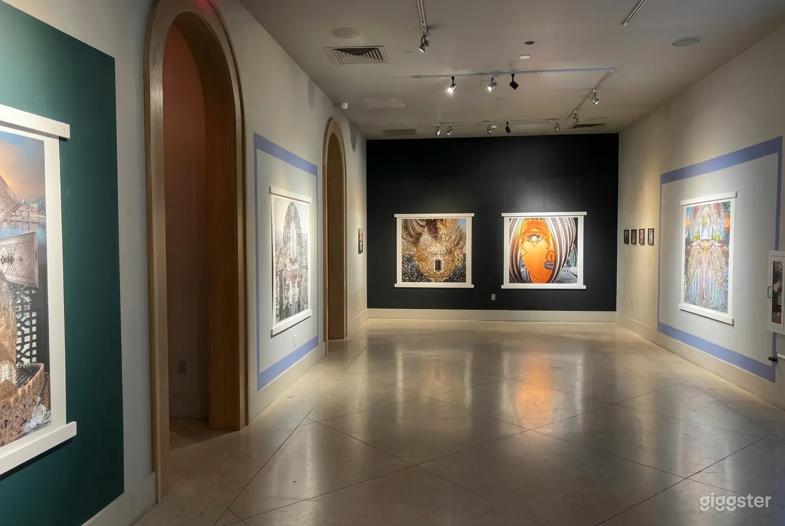 An art gallery with large paintings, walls of black and white, and two large arched doors.