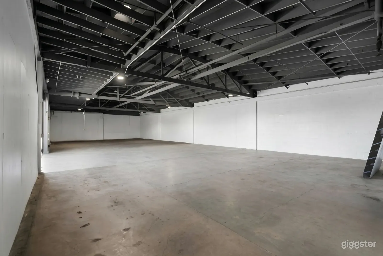 A large empty garage is painted white, with the ceiling supports painted in black.
