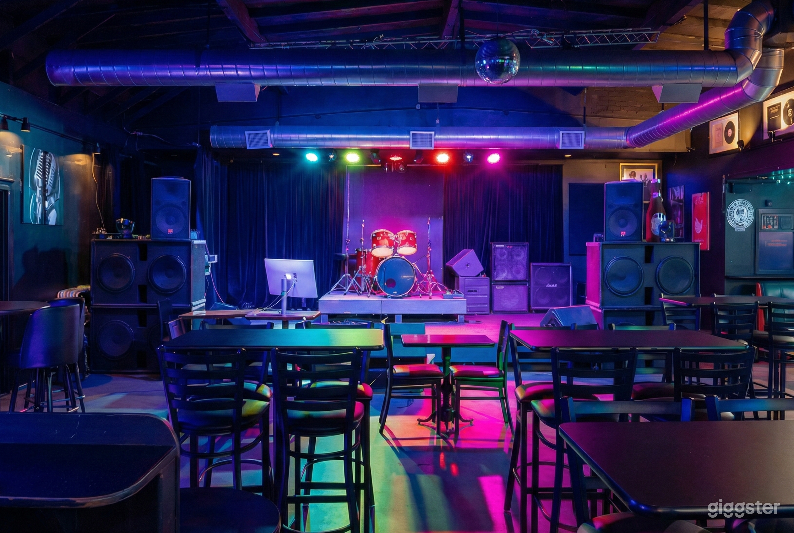 Colorfully lit party room with a drum set on the stage as a focal point.