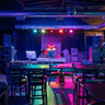 Colorfully lit party room with a drum set on the stage as a focal point.