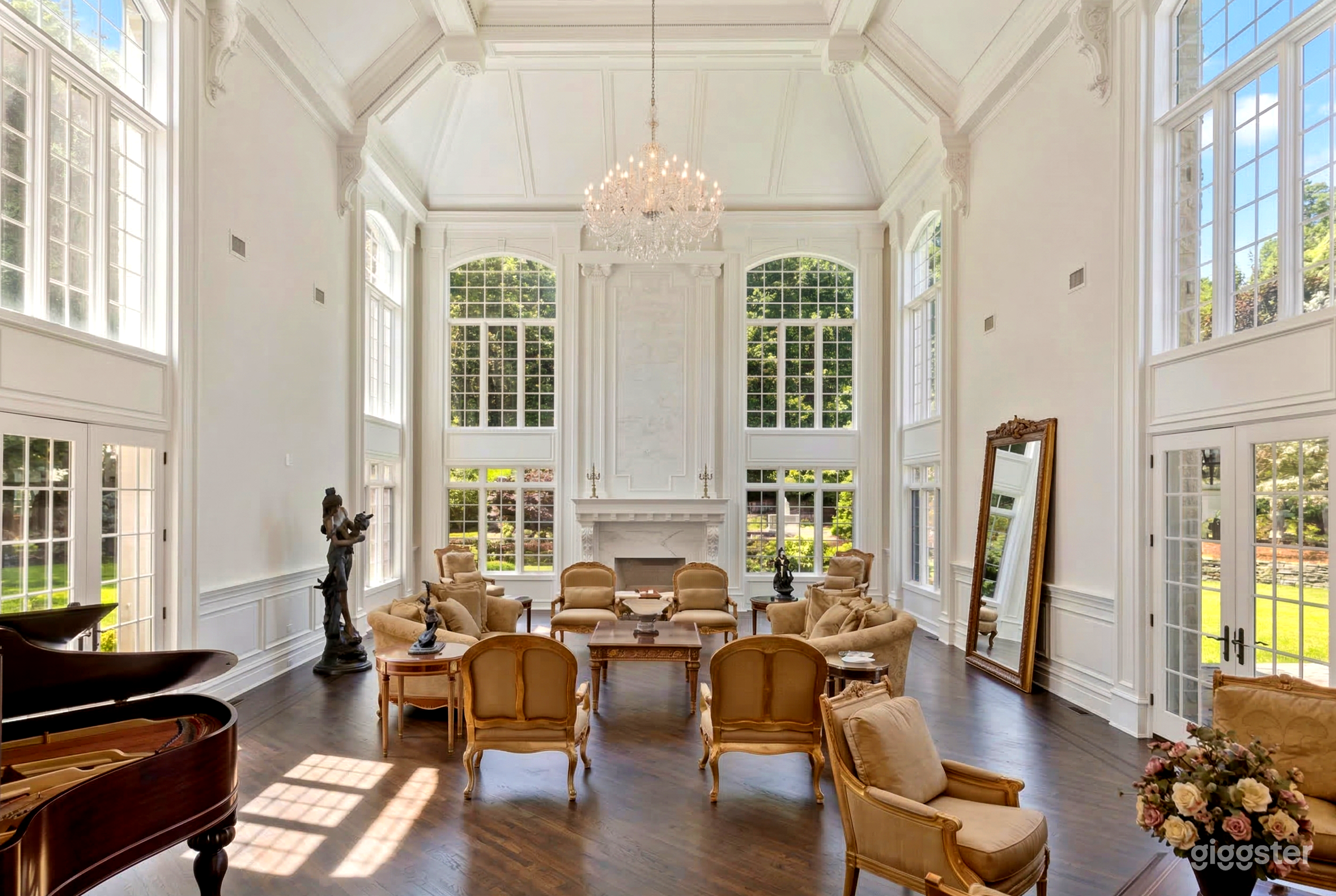 A high ceiling in a room filled window highlights the beige period furnishings below.