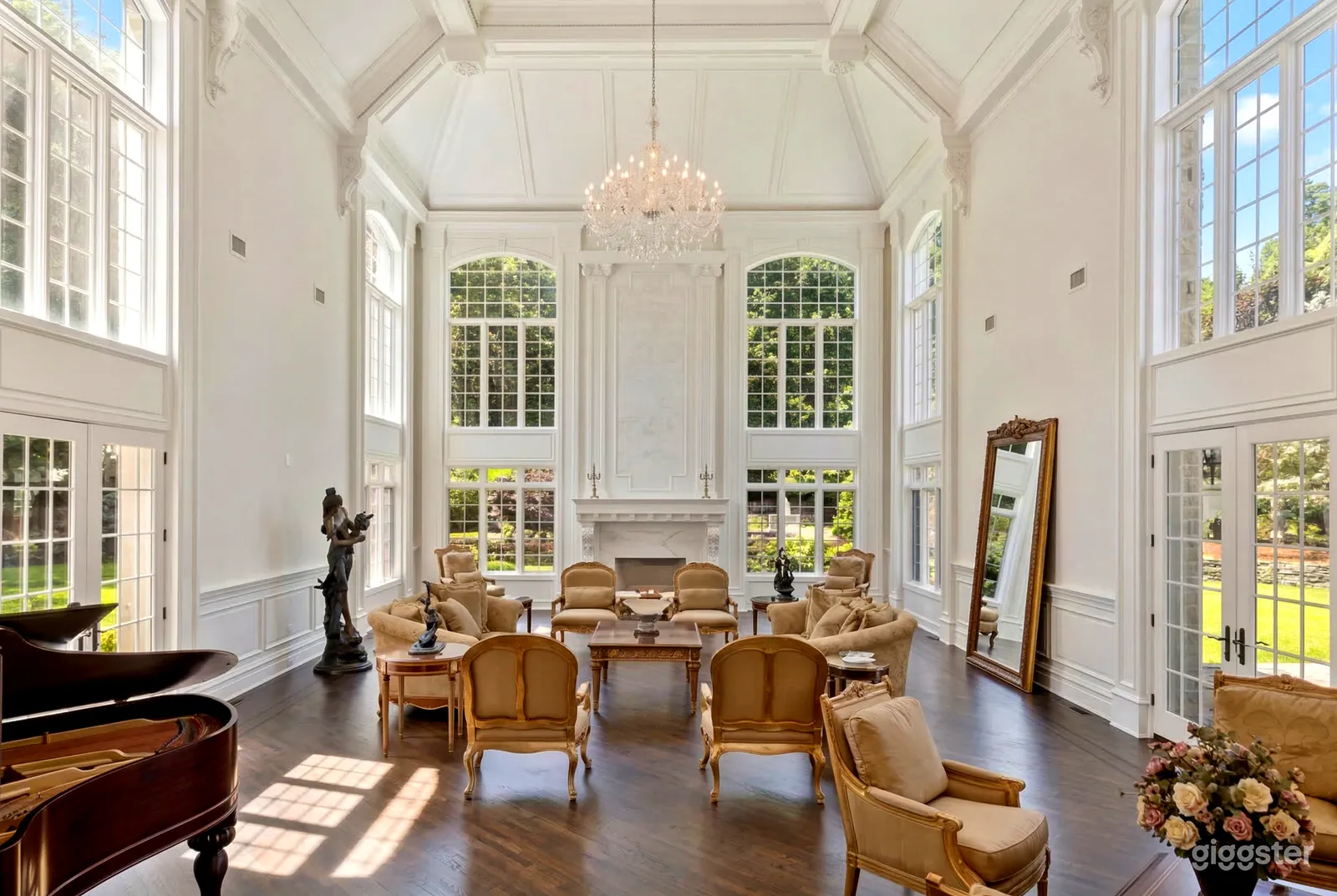 A high ceiling in a room filled window highlights the beige period furnishings below.