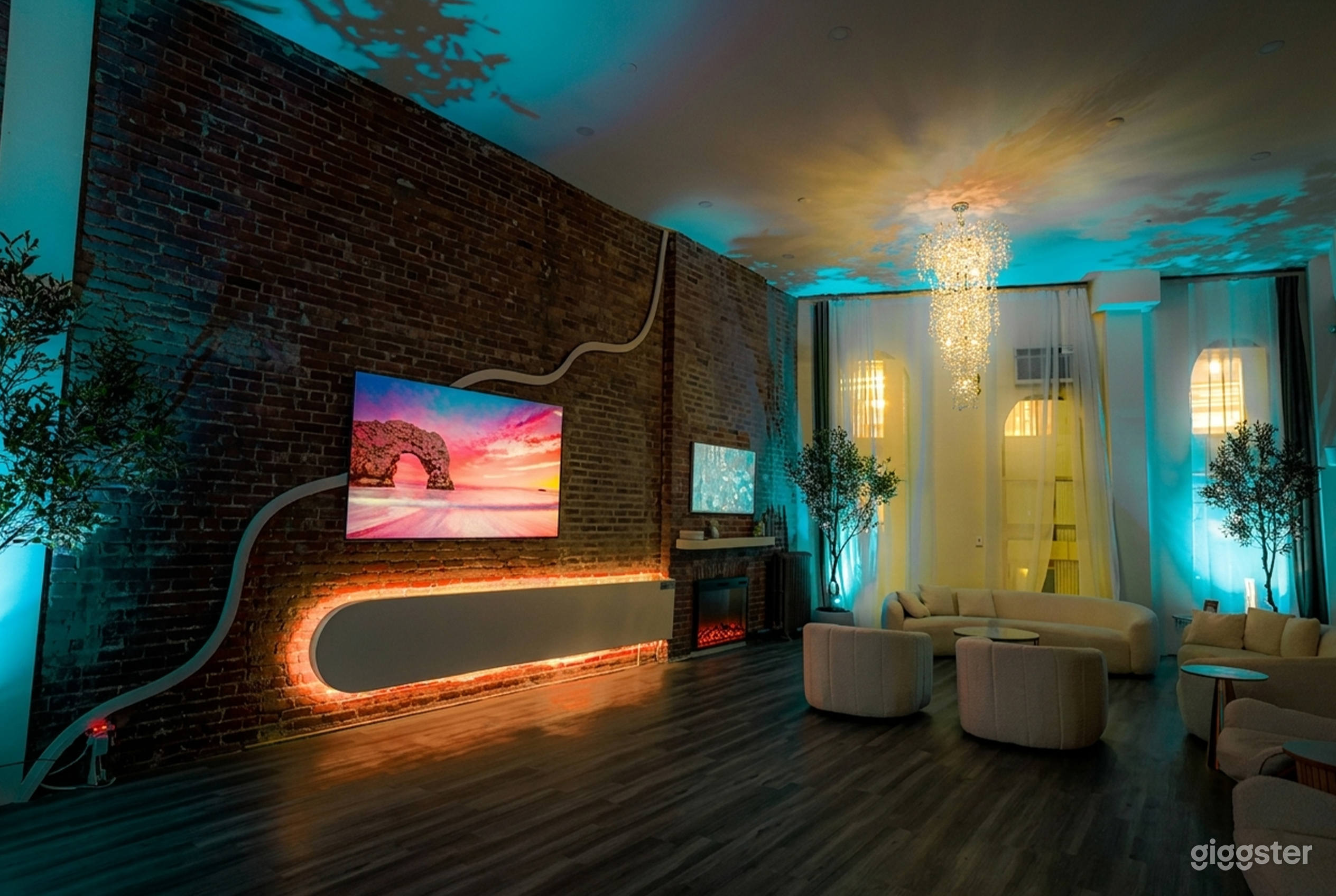 A television highlights the wall in a mid-century modern room with blue lighting and beige couches off to the side.