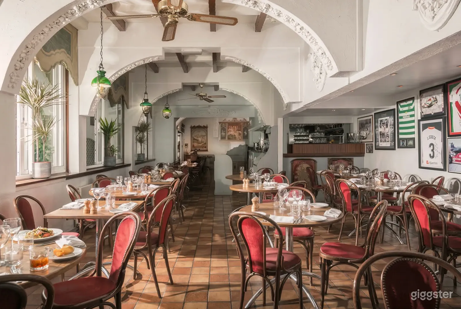 Cafe style tables with red chairs in a hacienda style restaurant with a curved ceiling.