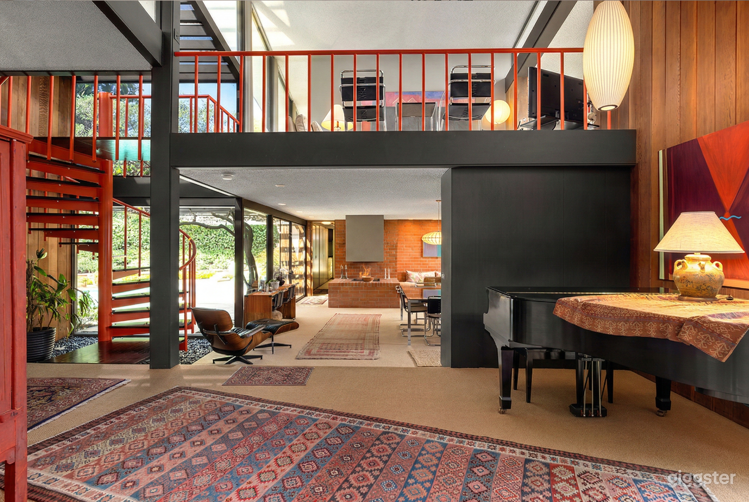 A mid century modern home with leather furniture, a spiral staircase and paneled walls.