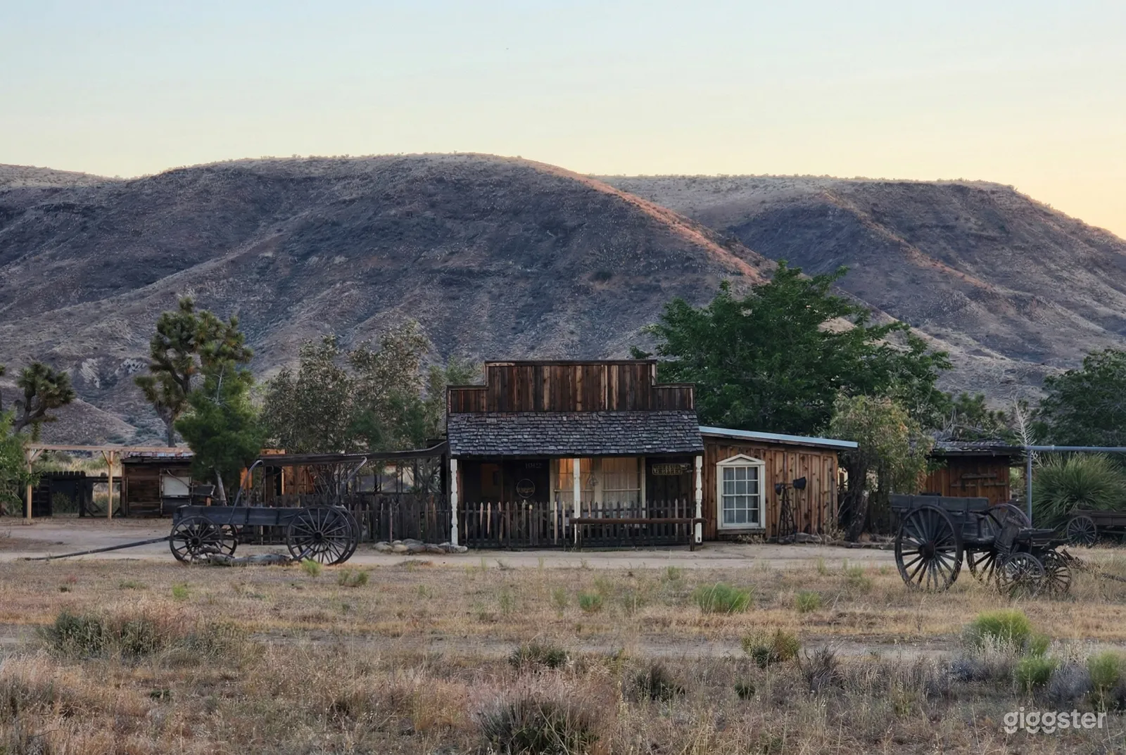 A ranch venue with wagons on either side has a backdrop of a mountain range.