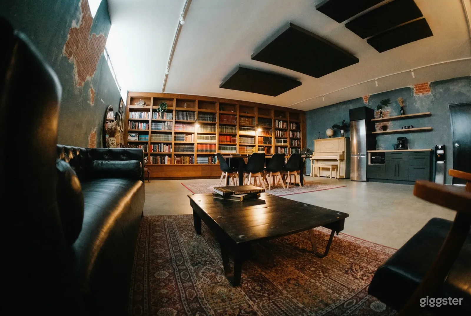 A large room has a wall of bookshelves, a table with chairs, a couch and a coffee table.