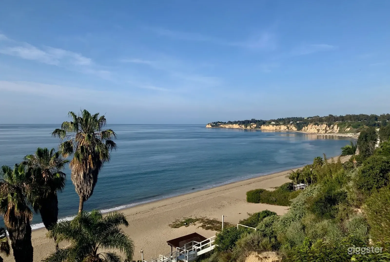 A sandy beach shore with cliffs in the distance overlooks the ocean.