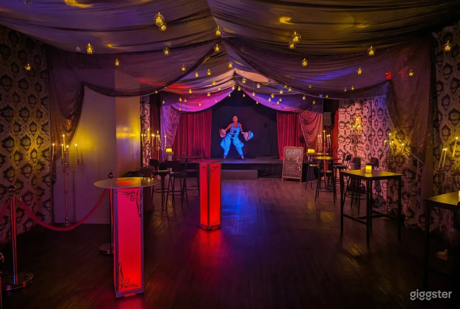 A dancer performs on a stage in a curtain-ceiling room with sporadic tables.