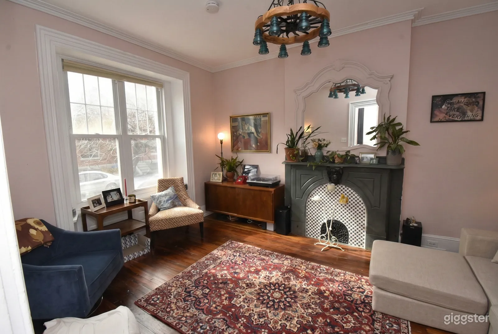 A carpeted living room with comfortable chairs facing a decorative fireplace.