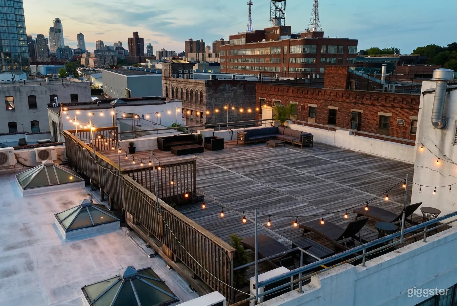 String lighting surrounds a large rooftop area that has minimal furniture.