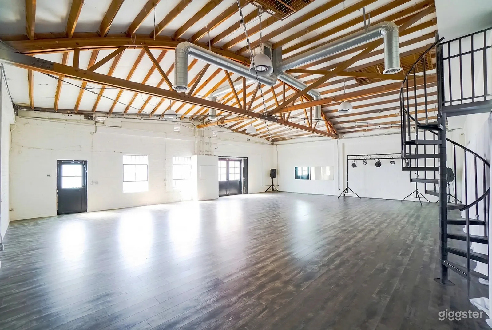 A large industrial space with metal ceiling beams, white walls and a shiny floor.