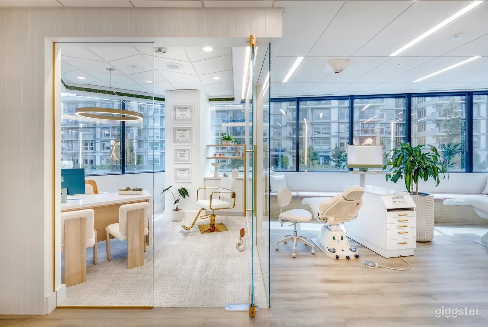 A dentist's office with desk and chairs sits beside an exam room, all with large windows.