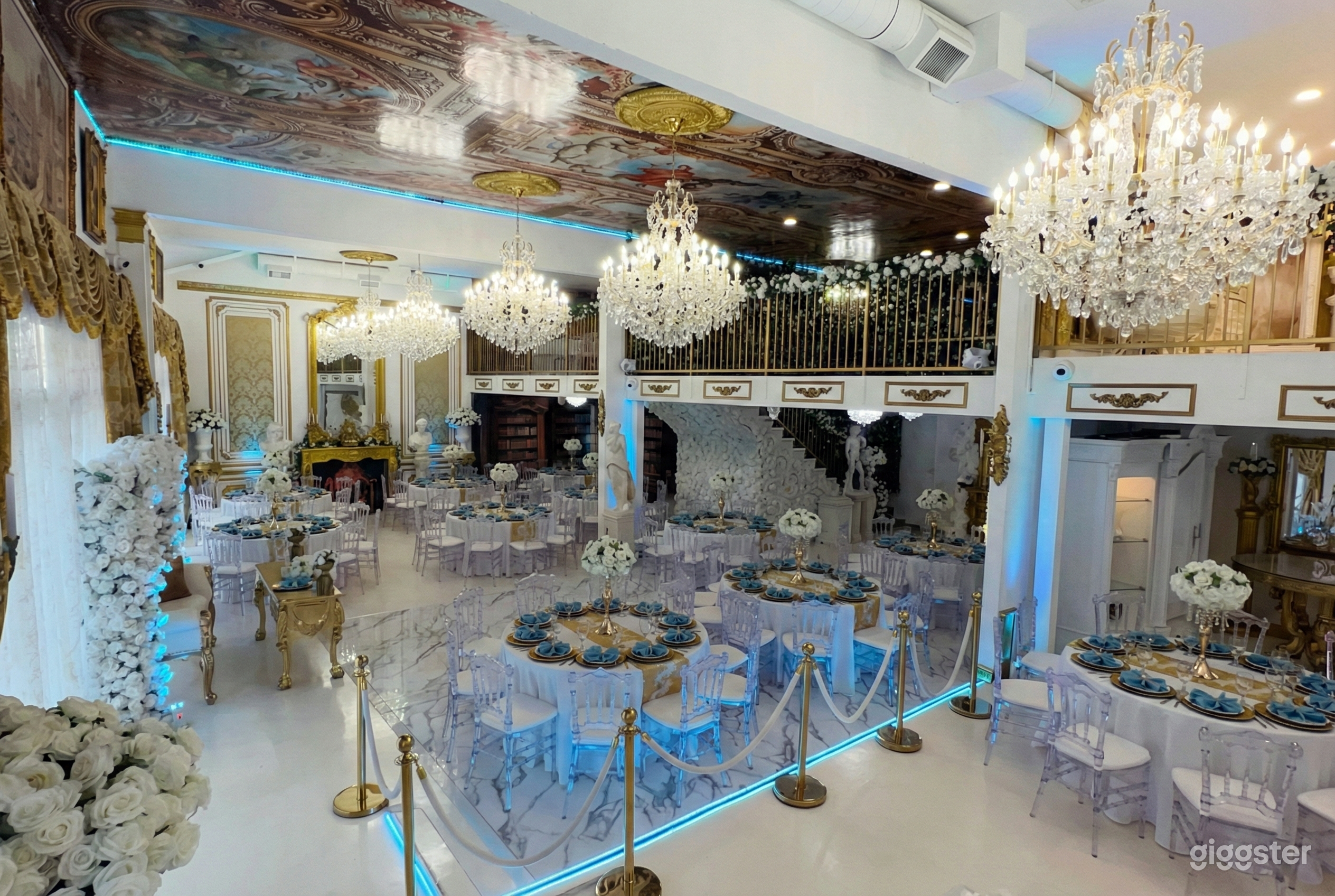 Ballroom decorated in blue and white with large crystal chandeliers as a focal point from the ceiling.