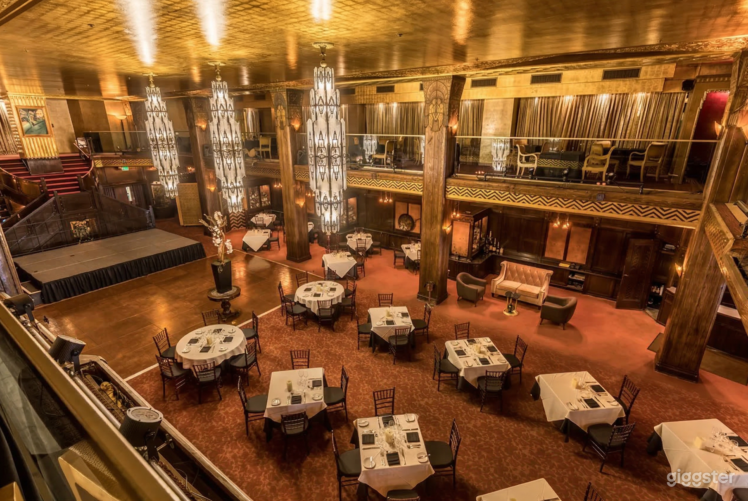 A ballroom style, two-level dining room with round and square tables set for a meal.