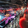 Bar venue with multiple seating and dancing zones lit in multicolored lights.