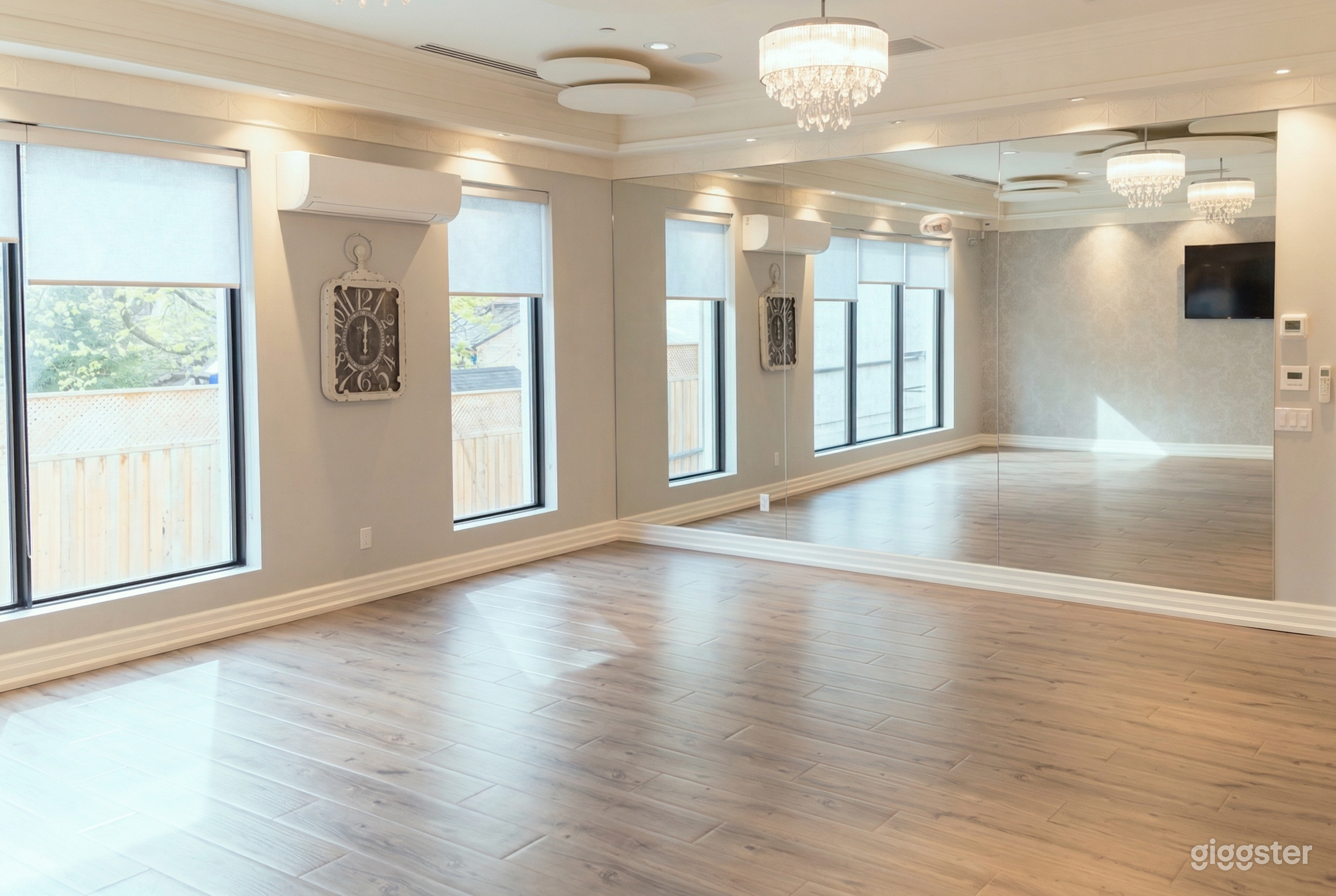 An empty studio type room with large windows and a mirrored wall.