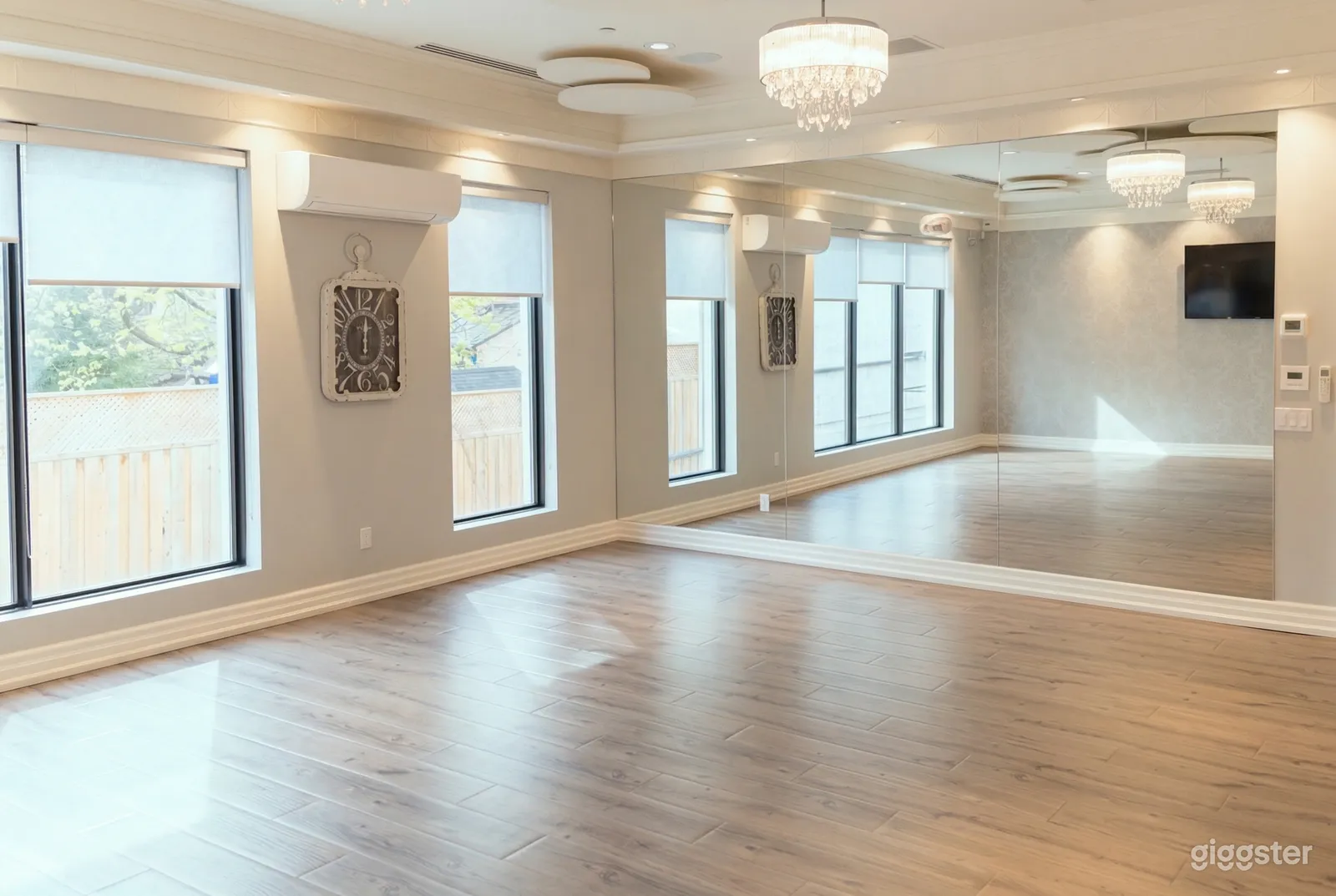 An empty studio type room with large windows and a mirrored wall.
