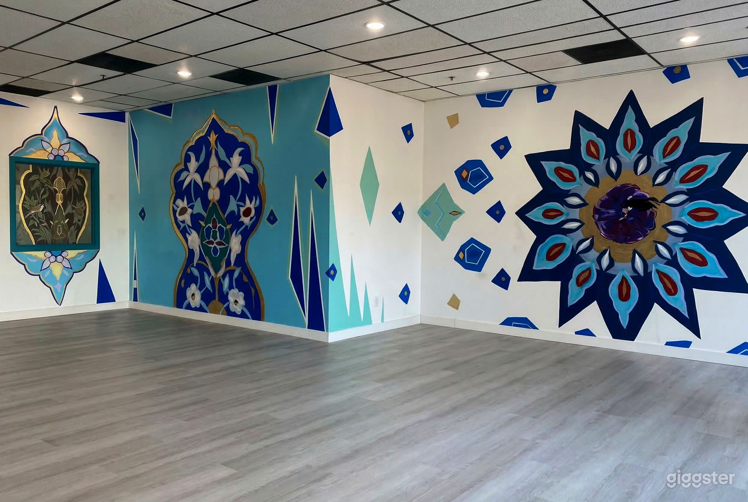 An empty studio room is decorated with vibrant blue murals on three visible walls.