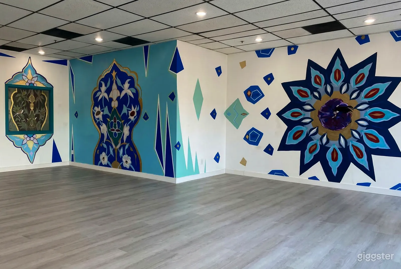 An empty studio room is decorated with vibrant blue murals on three visible walls.