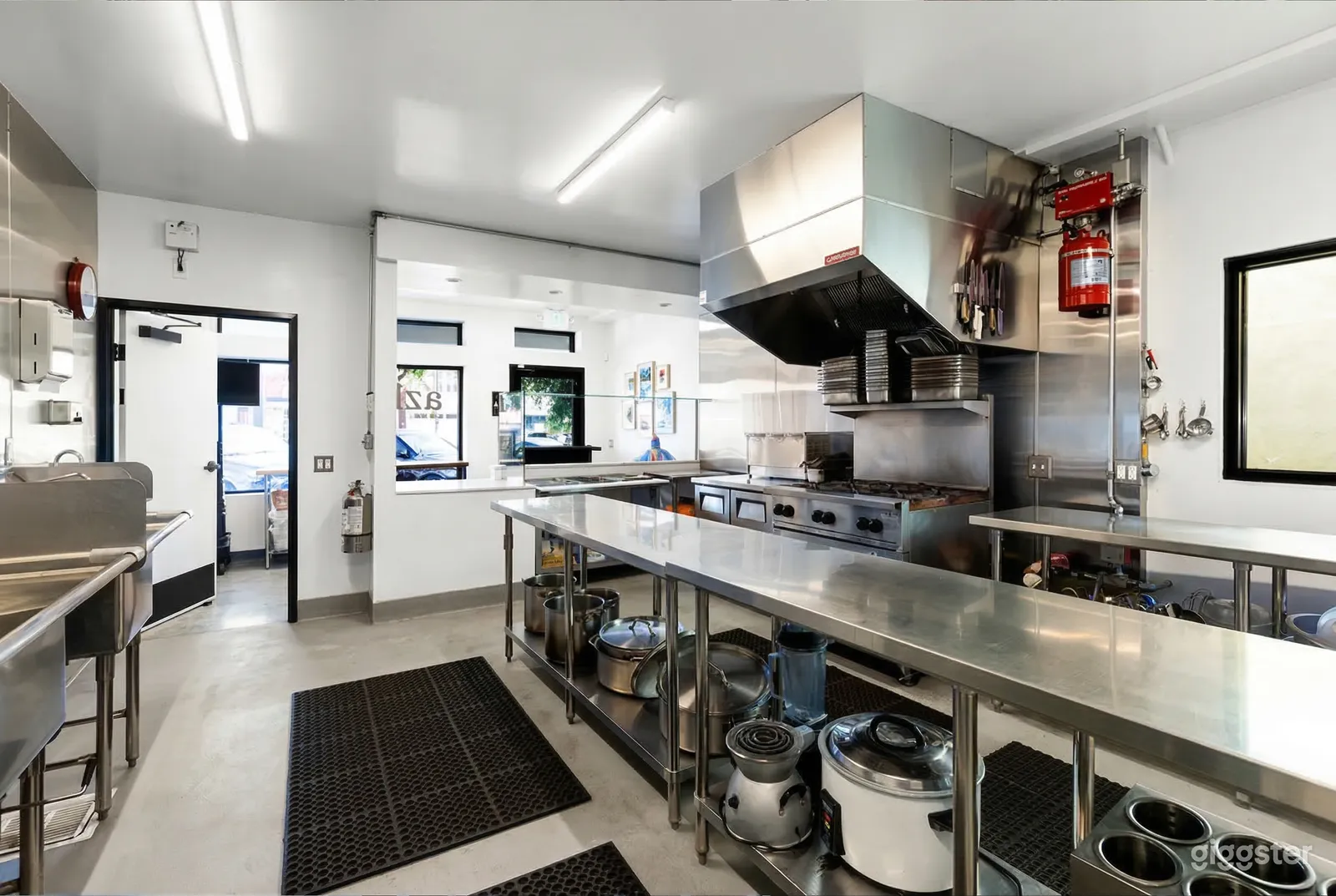 A stainless steel counter in a commercial kitchen, along with prep areas and a large stove.