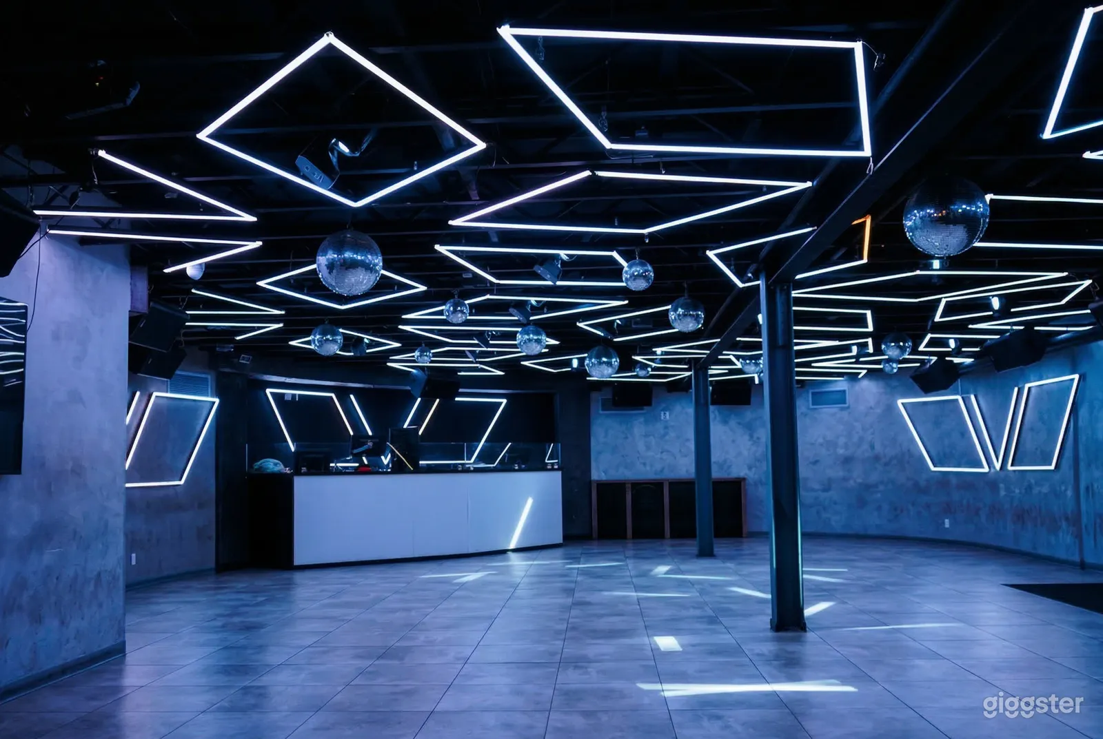 An event room has blue lighting and indigo hues on the walls and floor, with a sound booth in the background.