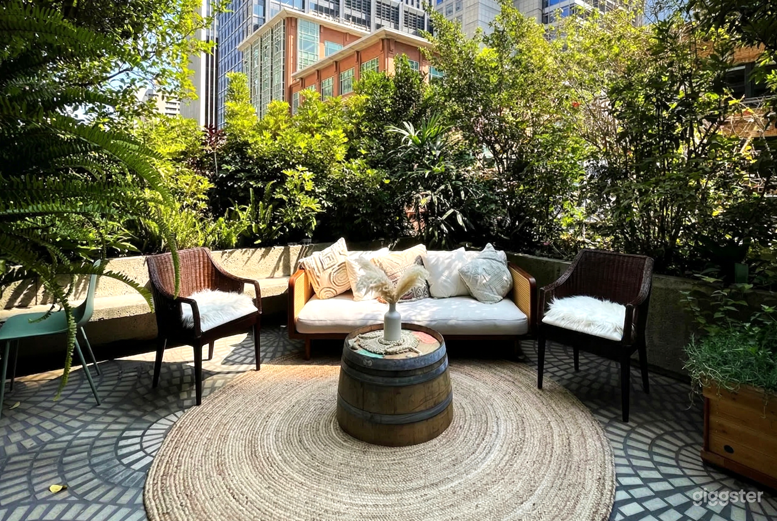 A burlap rug sits under outdoor furniture on an outdoor patio surrounded by trees.