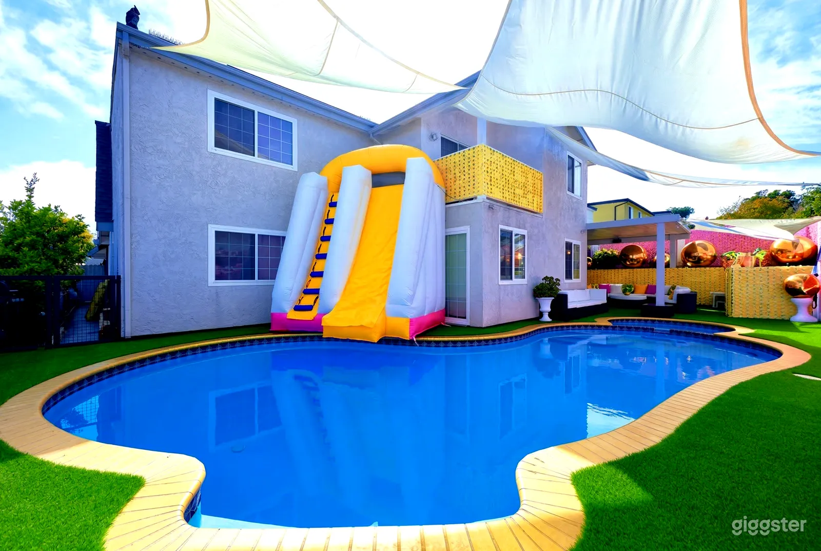 A bright fabric slide is central to a colorful backyard with an inground pool.
