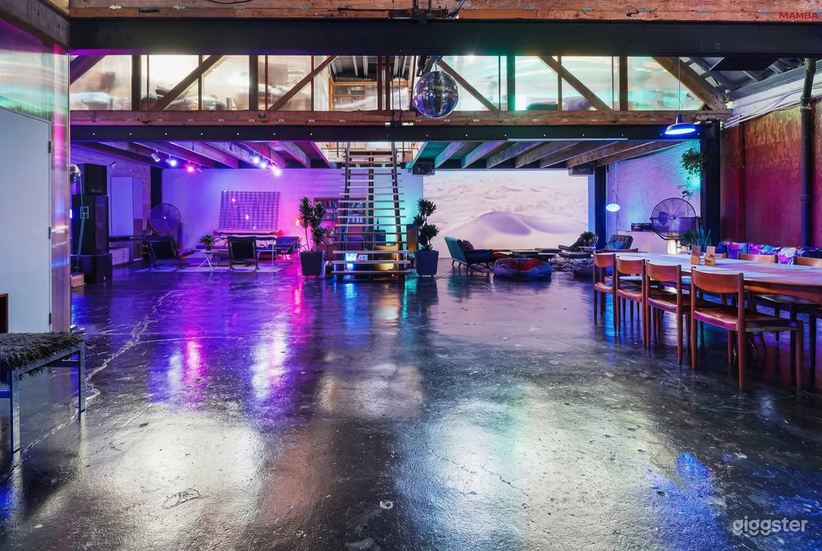 The cement floor shines in colorful hues in an industrial style room with a bare central staircase.