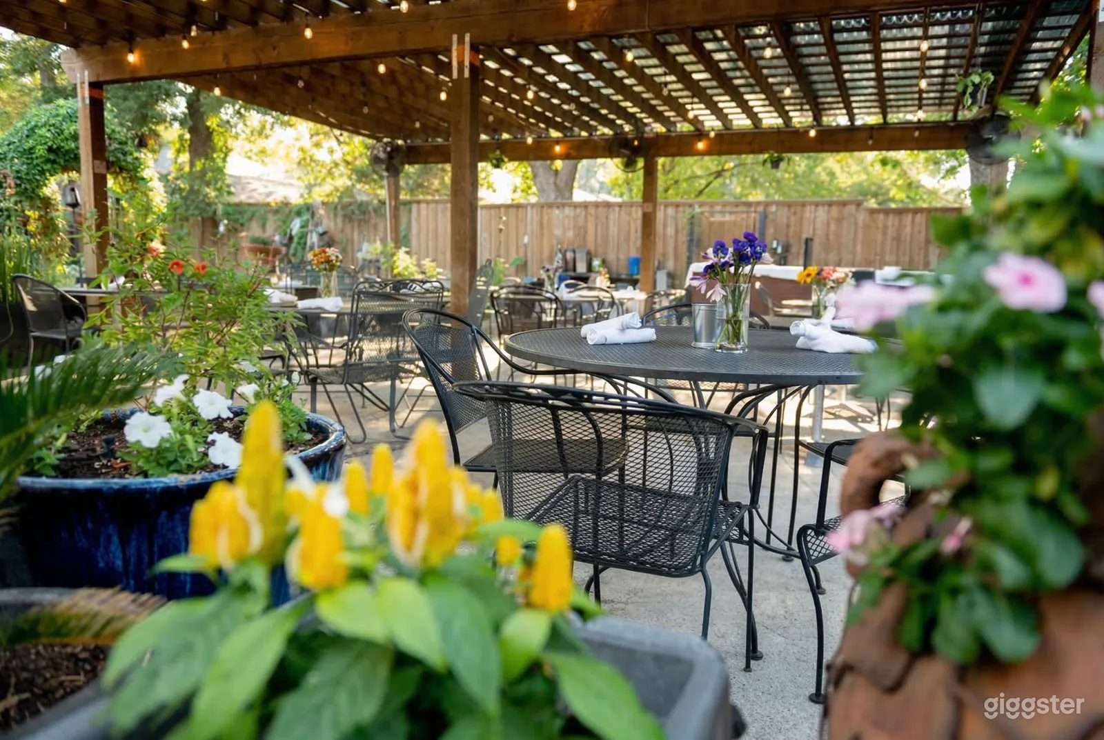 A garden terrace has black wrought iron tables and chairs with wildflower centerpieces on the tables.