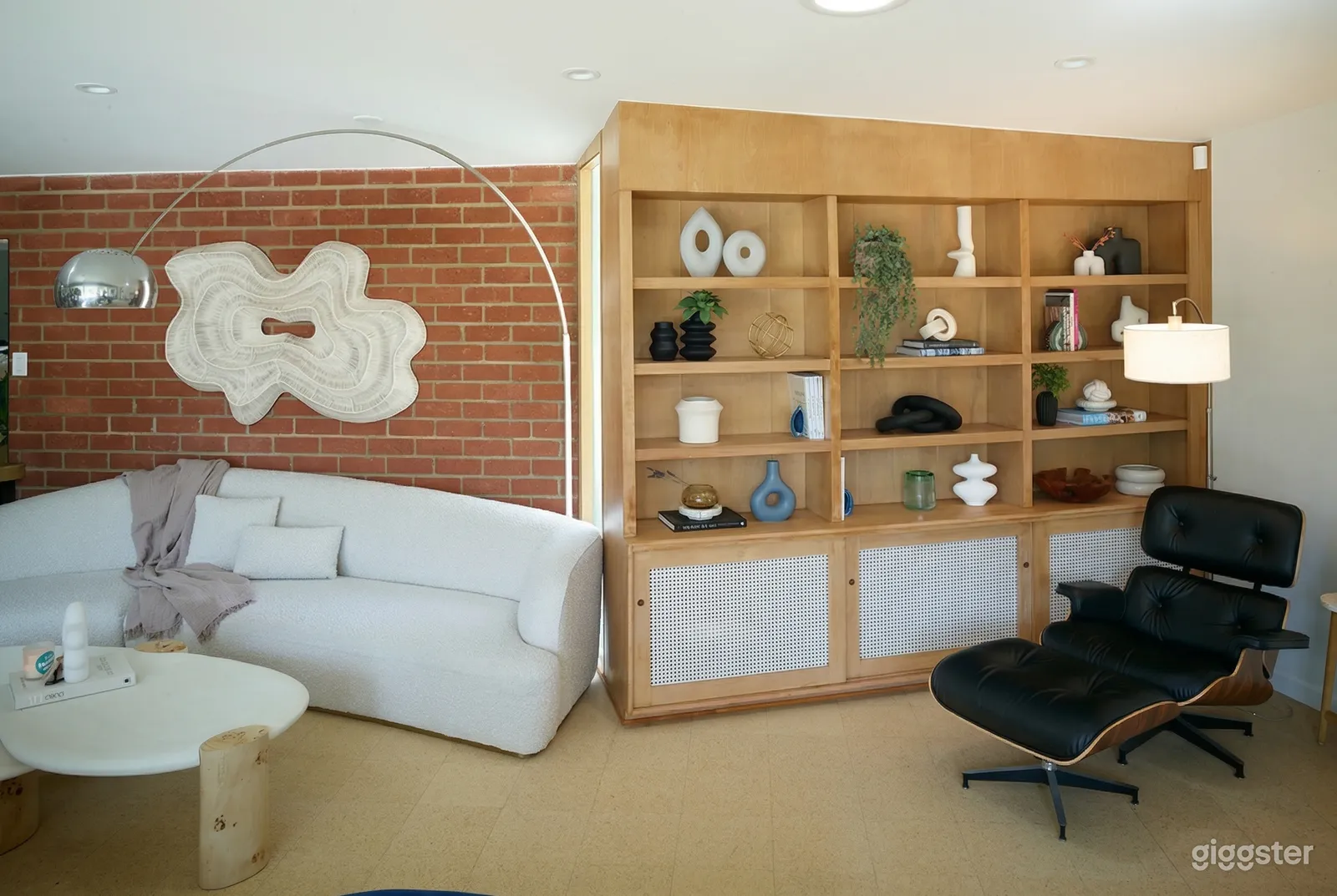 Brown shelving with modern decor and a white couch line a brick wall in a room set up for casting interviews.