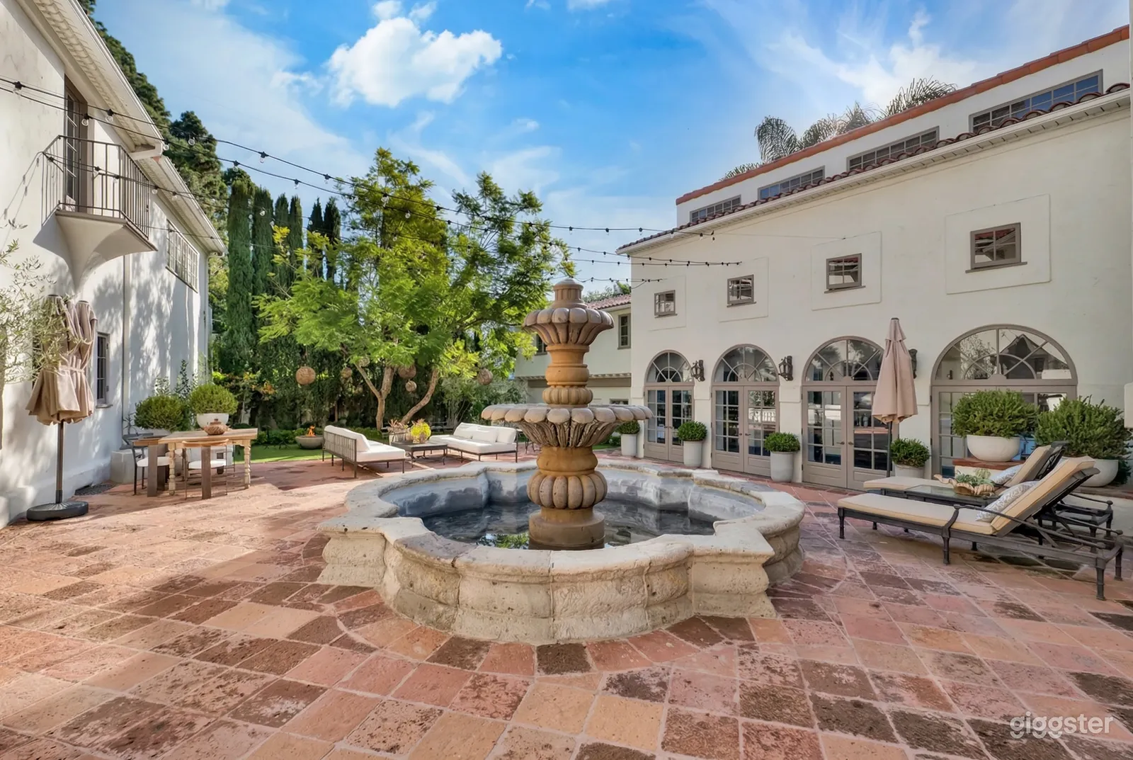 An ornate cement fountain sits in the central courtyard with hacienda style buildings surrounding it.