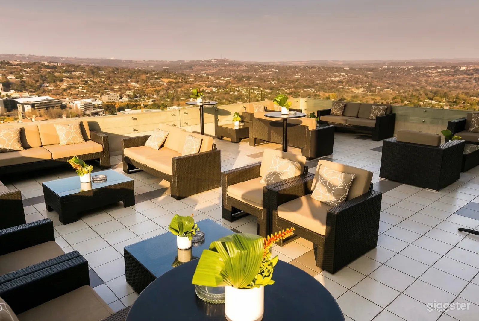 Outdoor tables, chairs and couches cover a sunny rooftop terrace.