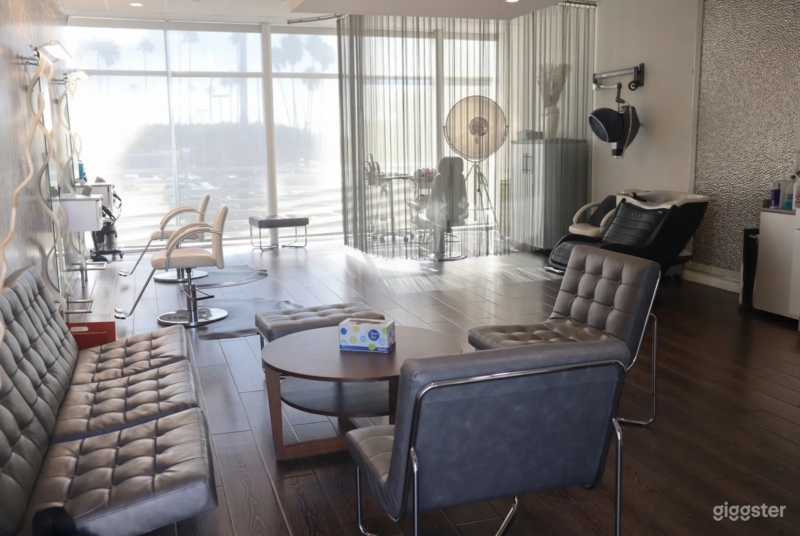 A bright and modern salon with leather seating, styling stations and a wall of windows.